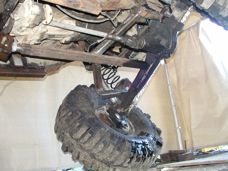 Off-road vehicle's heavily modified suspension with large tire, custom linkages, and differential