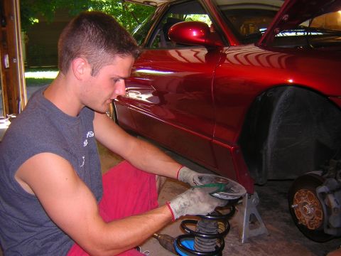 1995 Ford Probe - A man works on the suspension of a red 1995 Ford Probe.