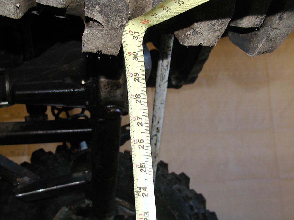 Measuring tire clearance with a tape measure against a vehicle's suspension and tire