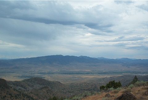 1986 Ford Bronco - Expansive view of a valley and mountains under a dramatic, cloudy sky.