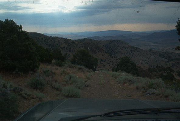 Interior view of a vehicle on a dirt road with mountainous scenery