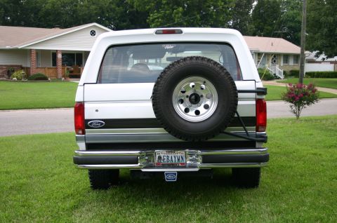1994 Ford Bronco - Rear view of a 1994 Ford Bronco parked on a grassy lawn in front of a house.