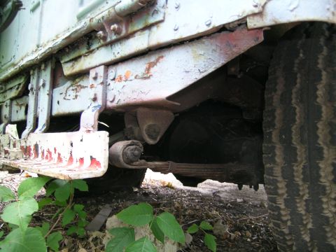 1950 Jeep CJ5 - Close-up view of the chassis and suspension system on a weathered Jeep, with visible rust and peeling paint.