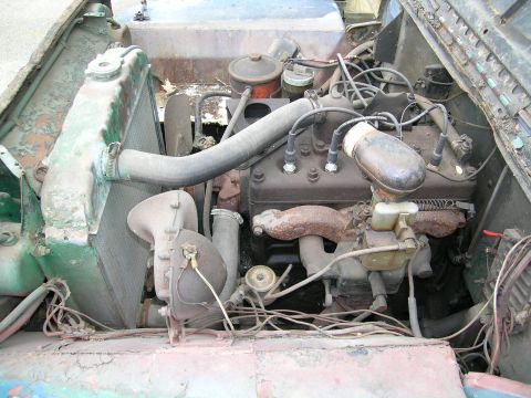 1950 Jeep CJ5 - The engine compartment of an older vehicle, with various mechanical components visible.