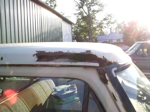 1979 Ford F-150 - Severe rust damage on the roof edge of a white truck, with another vehicle in the background.