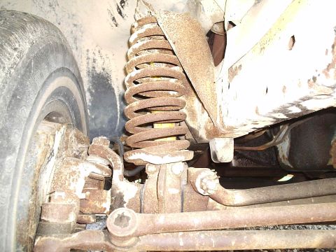 1979 Ford F-150 - Close-up view of the front suspension system, including the coil spring and tire, on a 1979 Ford F-150.