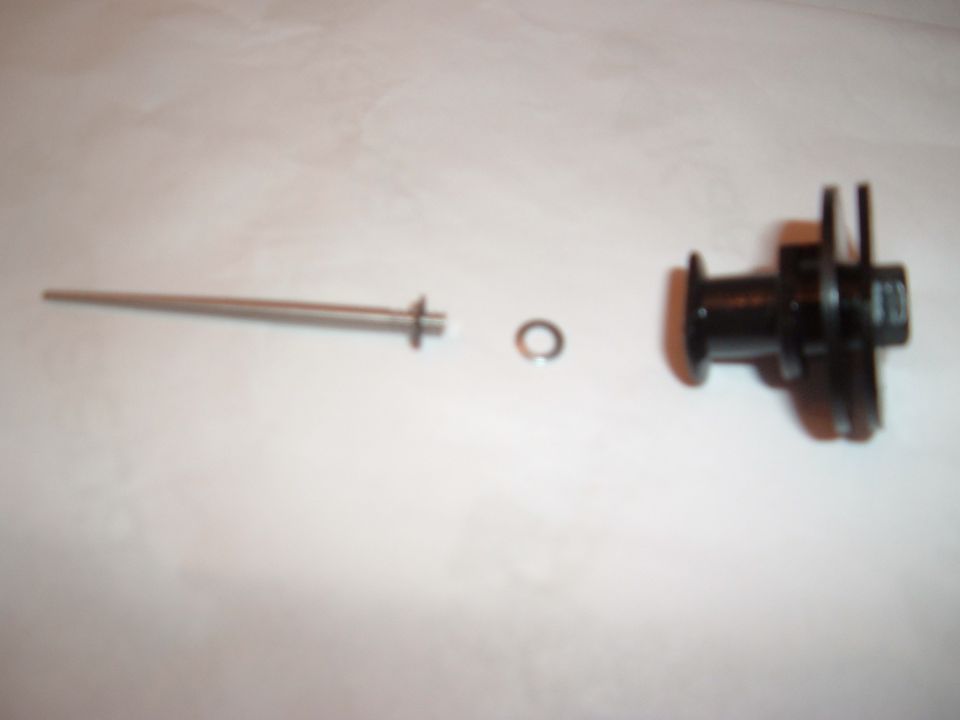 metal rod, washer, and black plastic component laid out on white surface