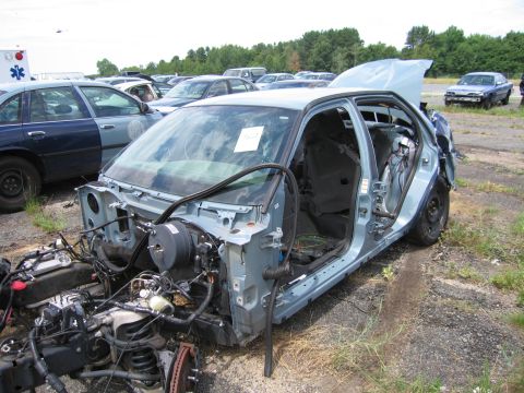1991 Ford LTD Crown Victoria - This car is missing many parts, including the engine, hood, and doors, in a junkyard setting.