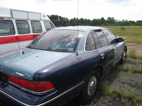 1991 Ford LTD Crown Victoria - A two-tone Ford Crown Victoria sedan is parked outdoors next to a white and red van.