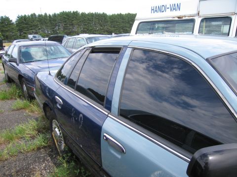 1991 Ford LTD Crown Victoria - A two-tone blue sedan is parked next to another vehicle, with a HANDI-VAN visible in the background.