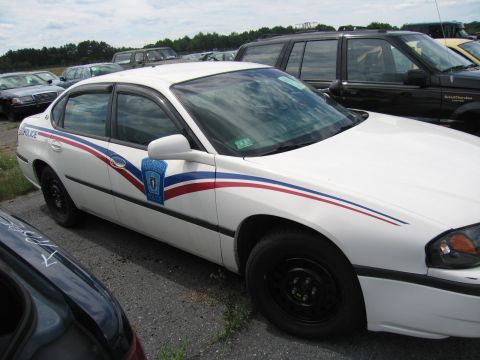 1991 Ford LTD Crown Victoria - A white police car with red and blue stripes is parked in a lot with other vehicles.