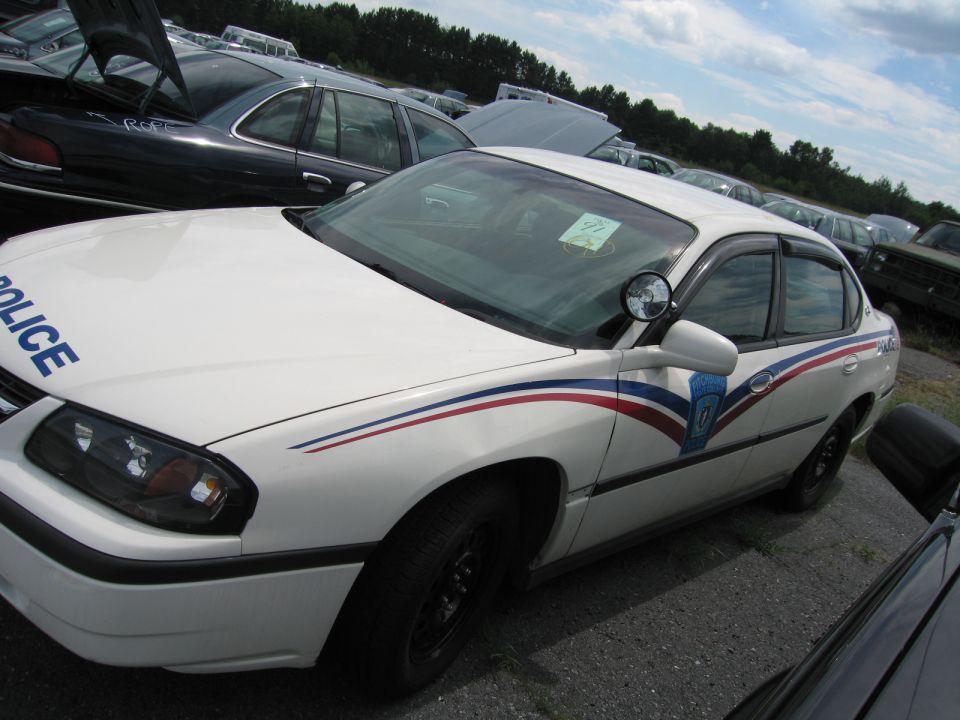 White police car with red and blue stripes on the side. "POLICE" is written on the hood