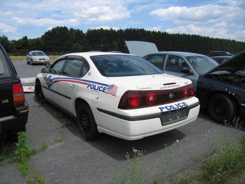 1991 Ford LTD Crown Victoria - A white police car is parked in an outdoor lot with its rear facing the camera, showing 'POLICE' markings.