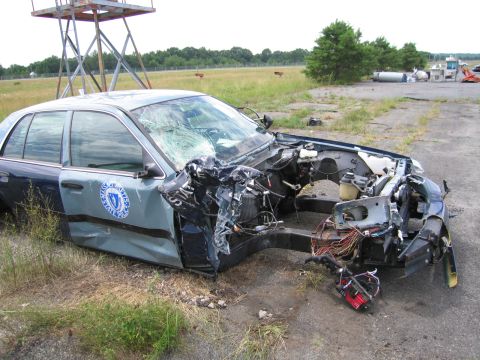 1991 Ford LTD Crown Victoria - A wrecked 1991 Ford Crown Victoria LTD police car sits abandoned in a field, its front end destroyed.