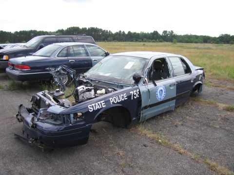 1991 Ford LTD Crown Victoria - Damaged 1991 Ford Crown Victoria LTD police car sits in a field with other vehicles in the background.