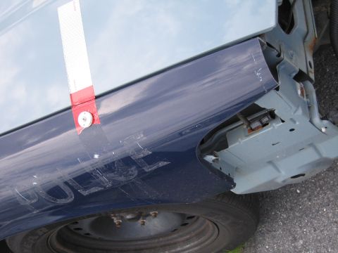 1991 Ford LTD Crown Victoria - A damaged police car fender with visible text and exposed internal structure.