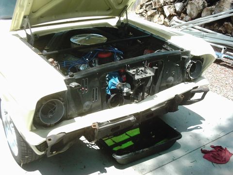 1978 Ford Bronco - Front end of a 1964 Ford Falcon with the hood up, showing the engine and missing bumper.