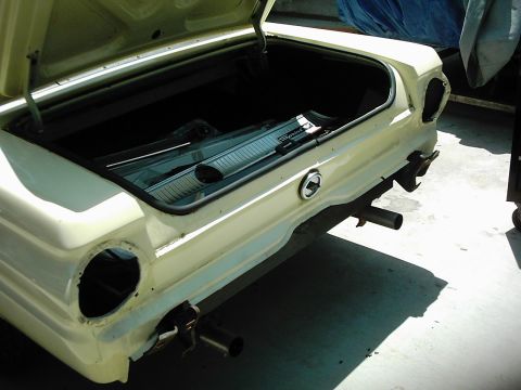 1978 Ford Bronco - The rear of a yellow 1964 Ford Falcon shows an open trunk and missing taillight assemblies.