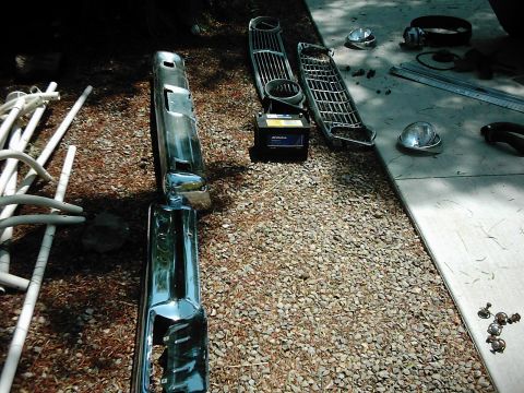 1978 Ford Bronco - Chrome bumper and two grilles are displayed on the ground, along with a car battery and other parts.