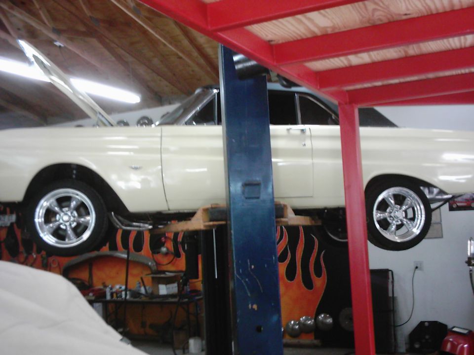 Cream-colored 1964 Ford Falcon coupe on a lift, hood open