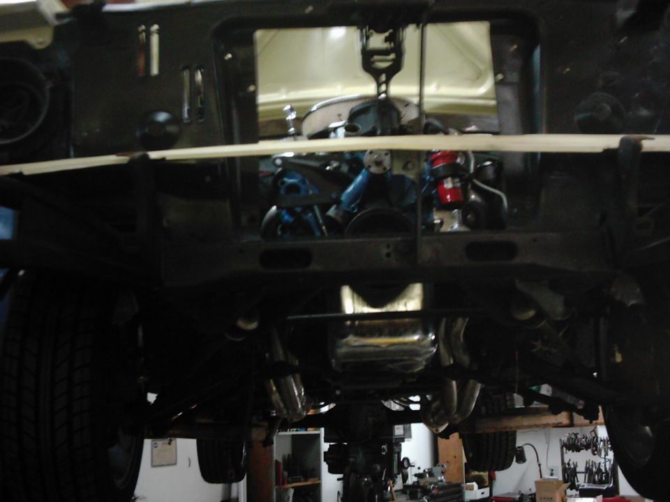 Underside view of a vehicle's engine bay with engine components visible, possibly during a repair or restoration