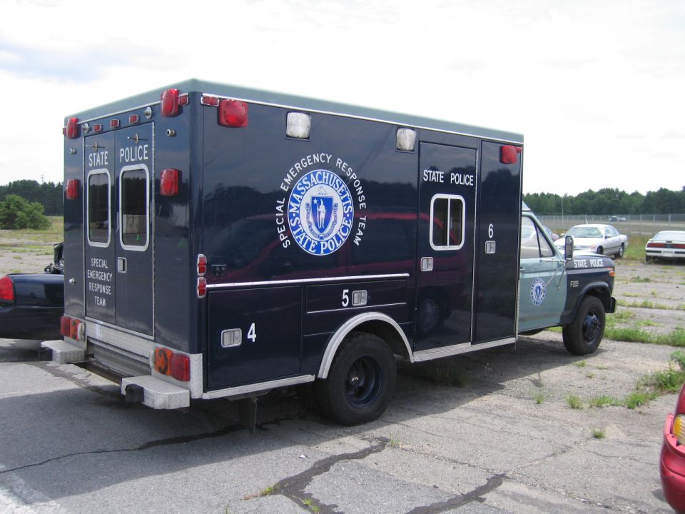 Dark blue Massachusetts State Police ambulance with "Special Emergency Response Team" text, parked on asphalt
