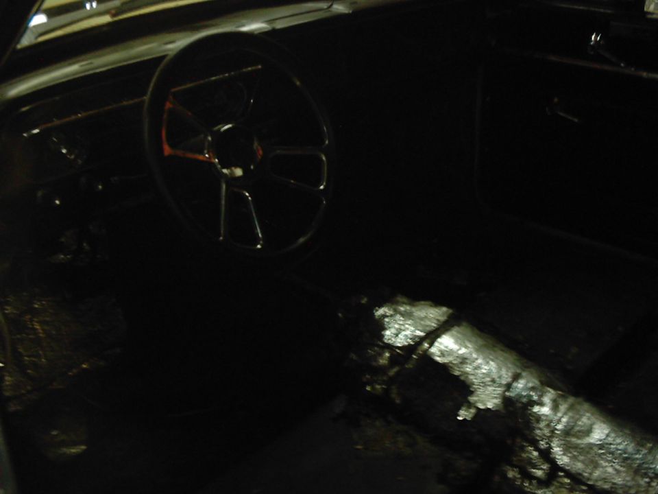 Interior shot of a car with a large steering wheel and a foil-covered center console