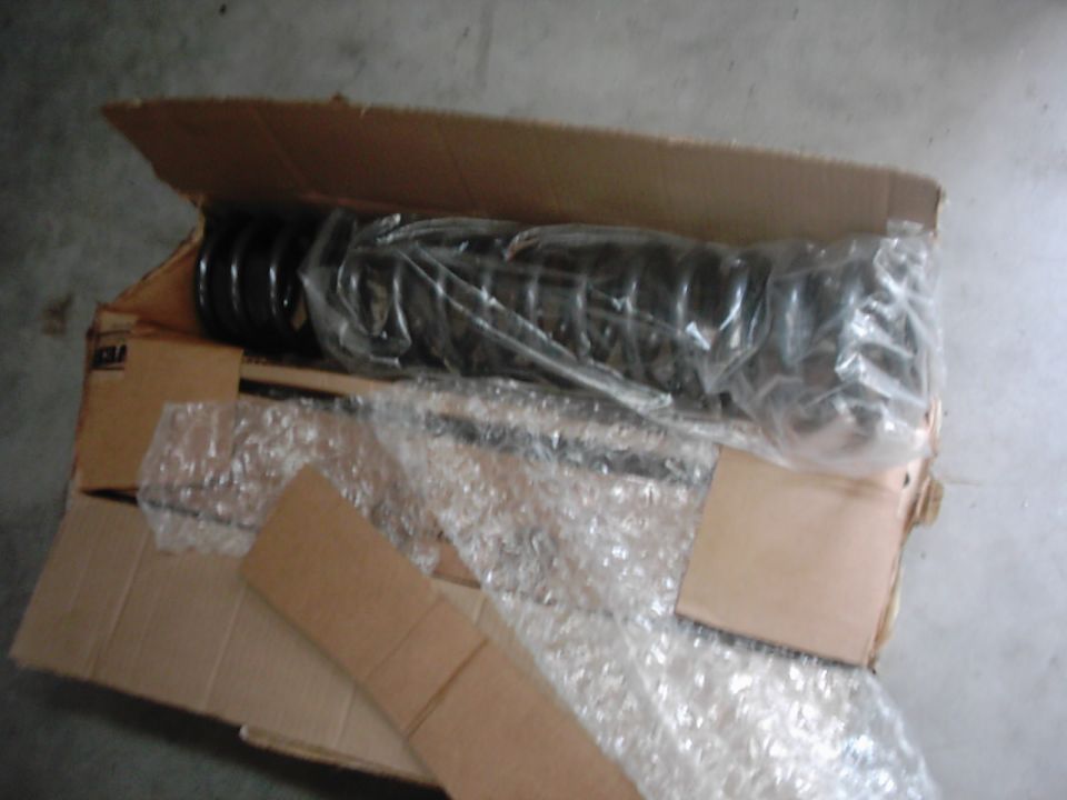 Suspension coil and shock absorber in a cardboard box, wrapped in plastic and bubble wrap