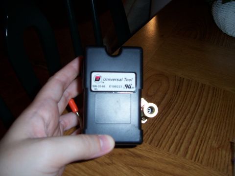 1983 Ford Bronco - A hand holds a black electronic module labeled 'Universal Tool' with an orange wire attached, resting on a wooden surface.