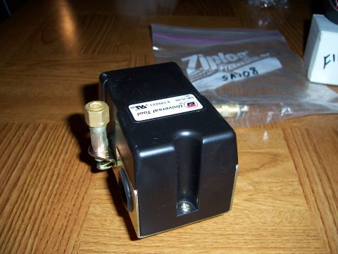 1983 Ford Bronco - A black pressure switch is shown on a wooden table next to a Ziploc bag and a white box.