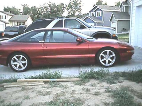 1996 Ford Probe - Red 1996 Ford Probe coupe parked next to an SUV in a residential driveway.