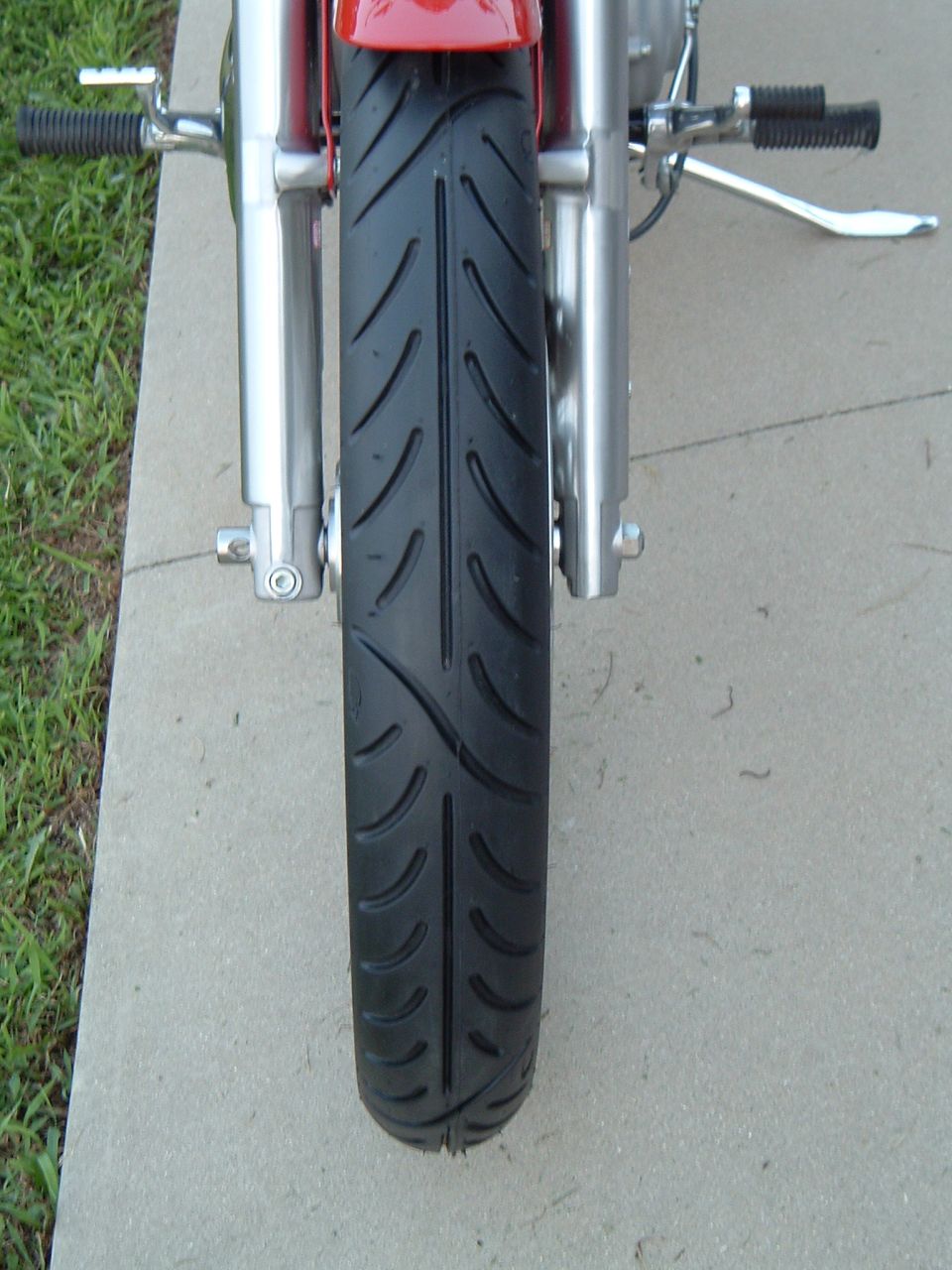 Motorcycle front tire and chrome forks, red bodywork visible above