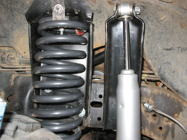 Coil spring and silver shock absorber in vehicle undercarriage suspension