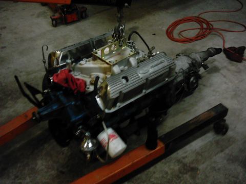 1978 Ford Bronco - Engine and transmission assembly, likely removed from a vehicle, sits on an orange engine stand.