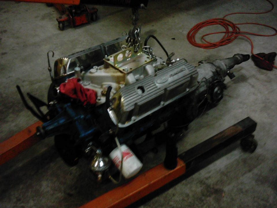 Engine and transmission assembly on an orange engine stand, with a red rag on top