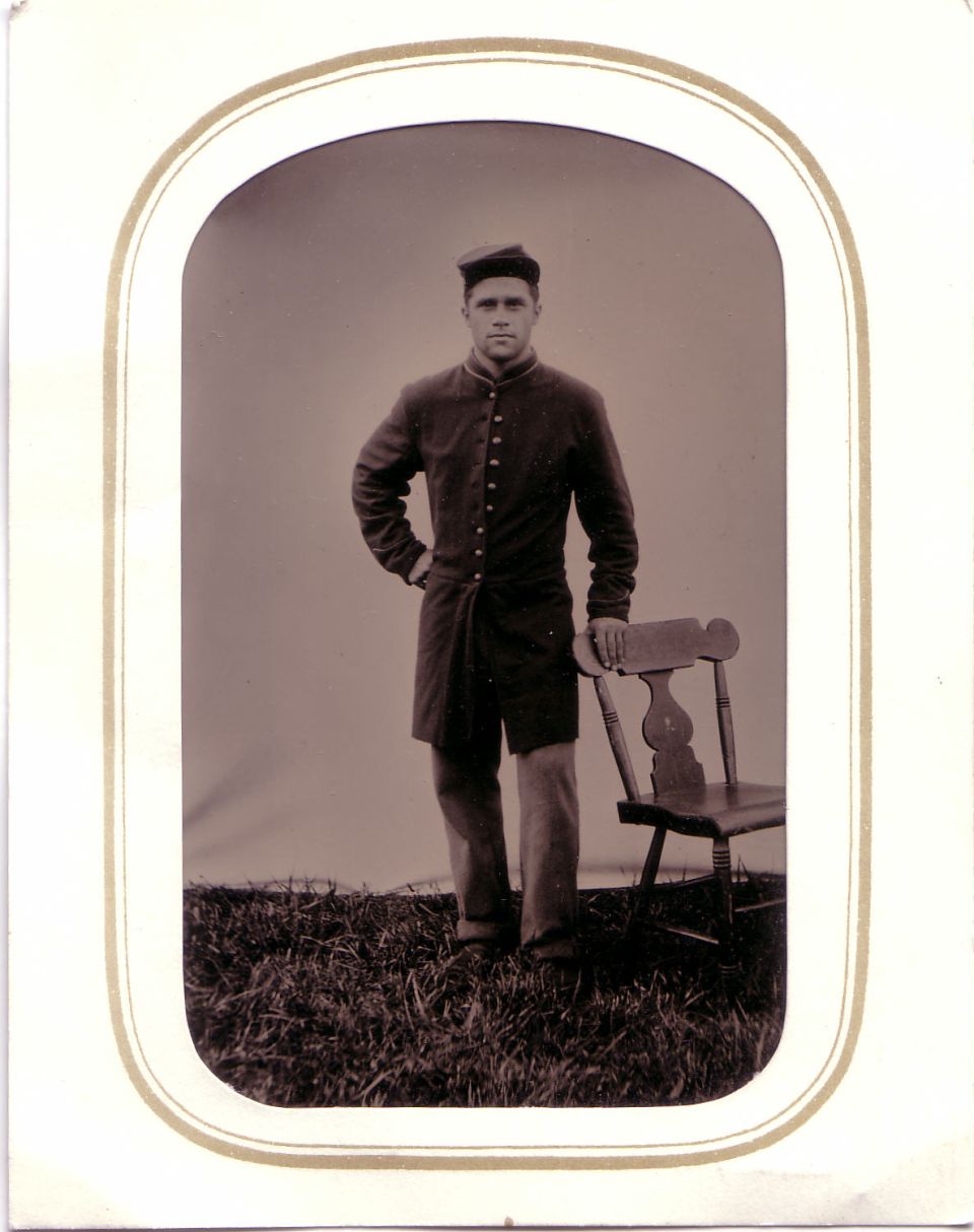 Man in uniform stands next to a wooden chair