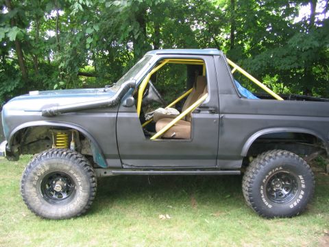 1986 Ford Bronco - This modified SUV features a snorkel, roll cage, and large off-road tires, suggesting it's built for terrain.