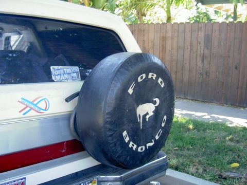 1988 Ford Bronco - The rear of a Ford Bronco is partially visible, with a spare tire cover prominently displayed.