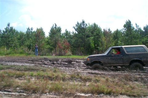 1988 Ford Bronco - A 1987 Ford Bronco tackles a challenging muddy terrain, demonstrating its off-road capabilities.