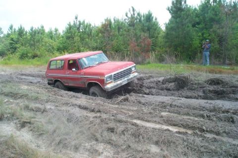 1988 Ford Bronco - A red 1978 Ford Bronco is stuck deep in the mud, with a person filming in the background.
