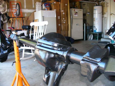1995 Ford Bronco - A close-up view of a black rear axle assembly supported by an orange jack stand in a cluttered garage setting.