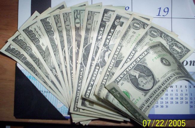Fan of US cash bills spread on a table next to a calendar, dated 07/22/2005