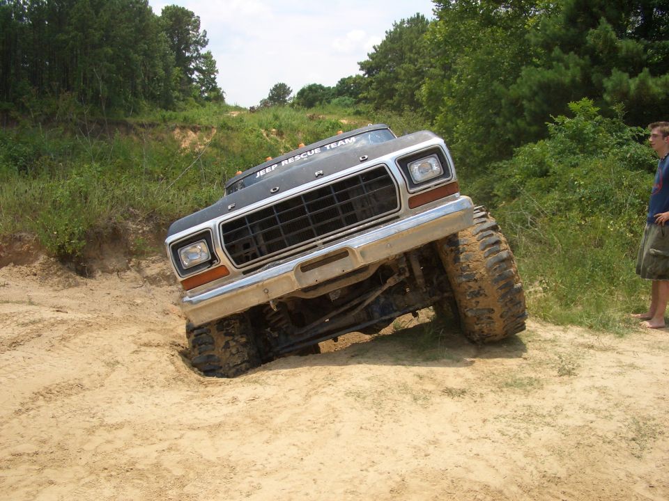 Ford F-Series truck with "JEEP RESCUE TEAM" on roof, stuck in sand off-road