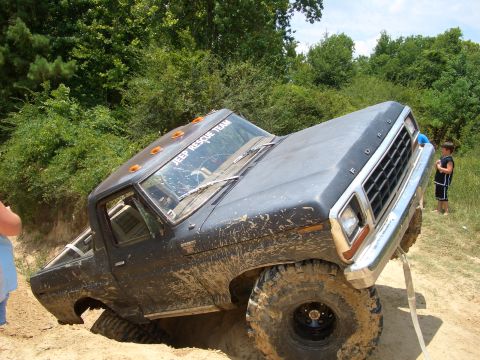 1990 Ford Bronco - A Ford pickup truck is stuck in the dirt, with a person in the background observing the situation.