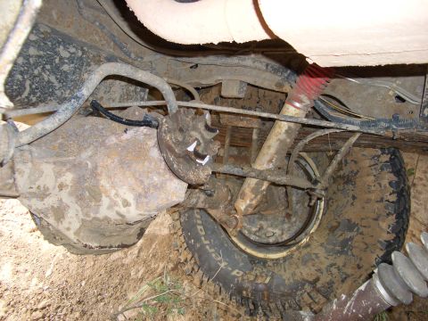 1990 Ford Bronco - Undercarriage view of a heavily soiled vehicle, focusing on the rear axle and suspension system.
