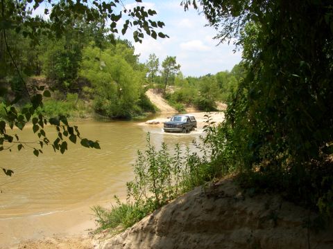 1990 Ford Bronco - Ford Bronco navigates a river crossing on a sunny day.