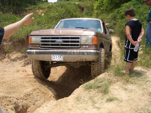 1990 Ford Bronco - 1990 Ford Bronco tackling an off-road trail with a young spectator.