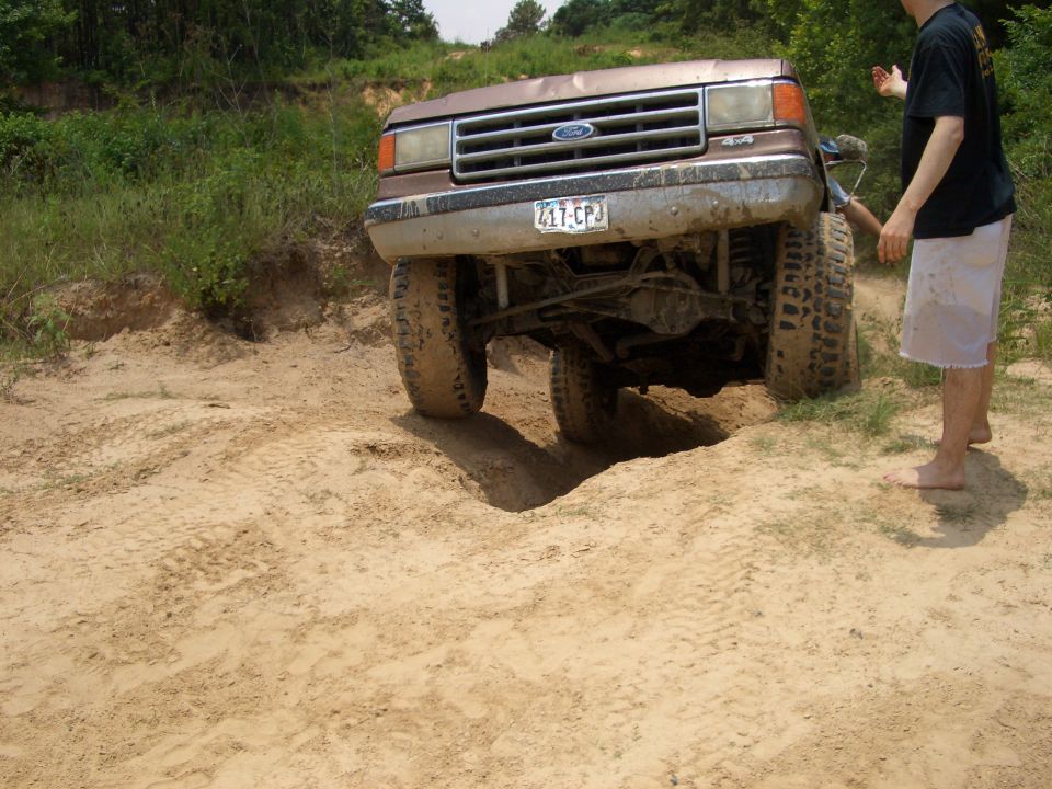 Ford F-Series truck with a dented hood going over a dirt mound. License plate 417-CPJ
