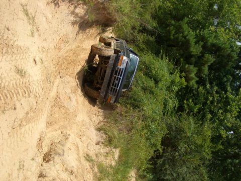 1990 Ford Bronco - A black 1990 Ford Bronco lies on its side after apparently rolling down a dirt embankment.