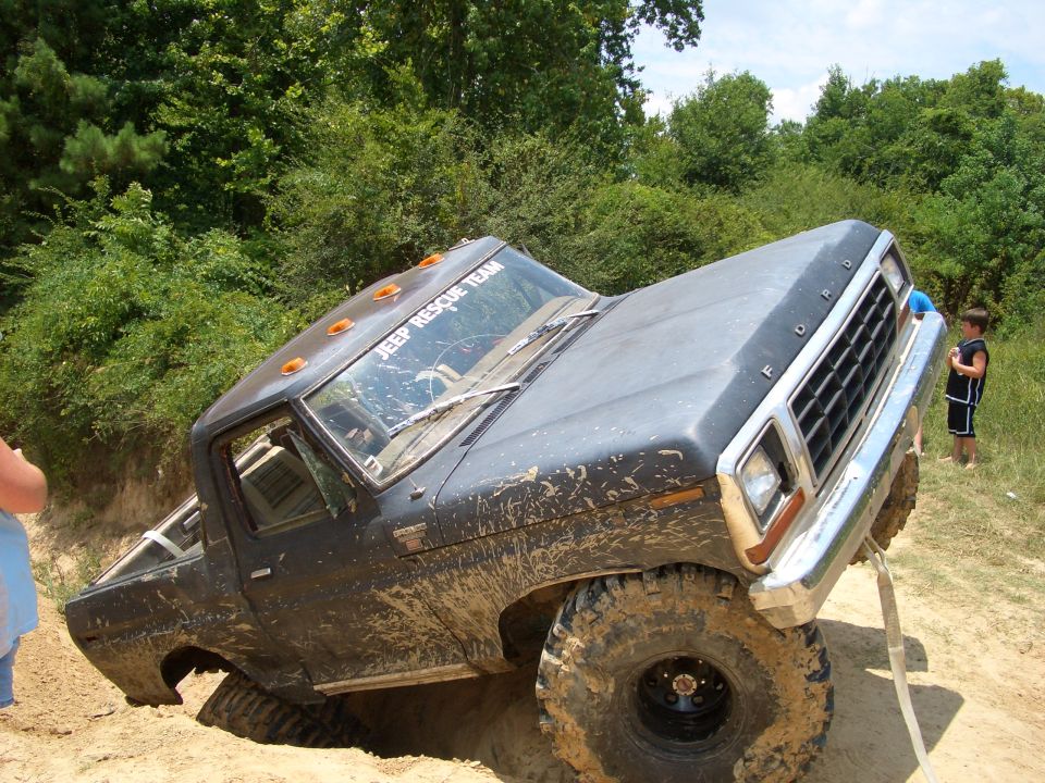 Muddy Ford pickup truck stuck in a ditch with a kid watching